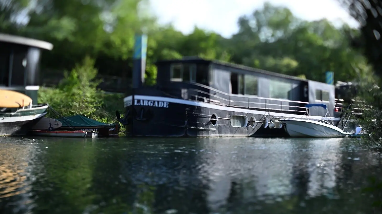 La péniche noire Largade amarrée sur la Seine, sous les arbres